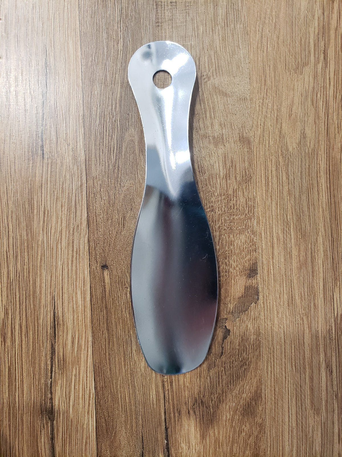 Allen's Bootery 7.5-inch professional silver metal shoe horn with a convenient hanging hole on a wood background.