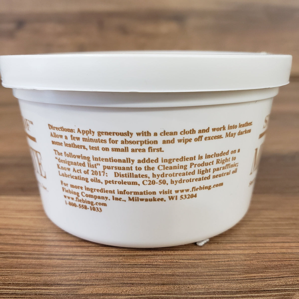 Allen's Bootery Snow-Proof Mink Oil paste container showing application instructions on a wooden surface
