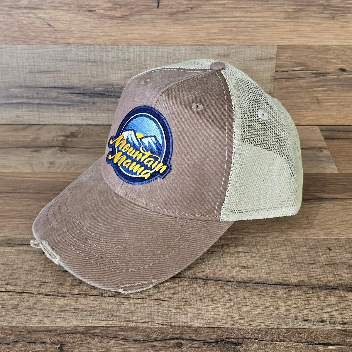 Allen's Bootery Mountain Mama trucker hat in brown with a distressed brim, mesh back, and embroidered mountain patch.