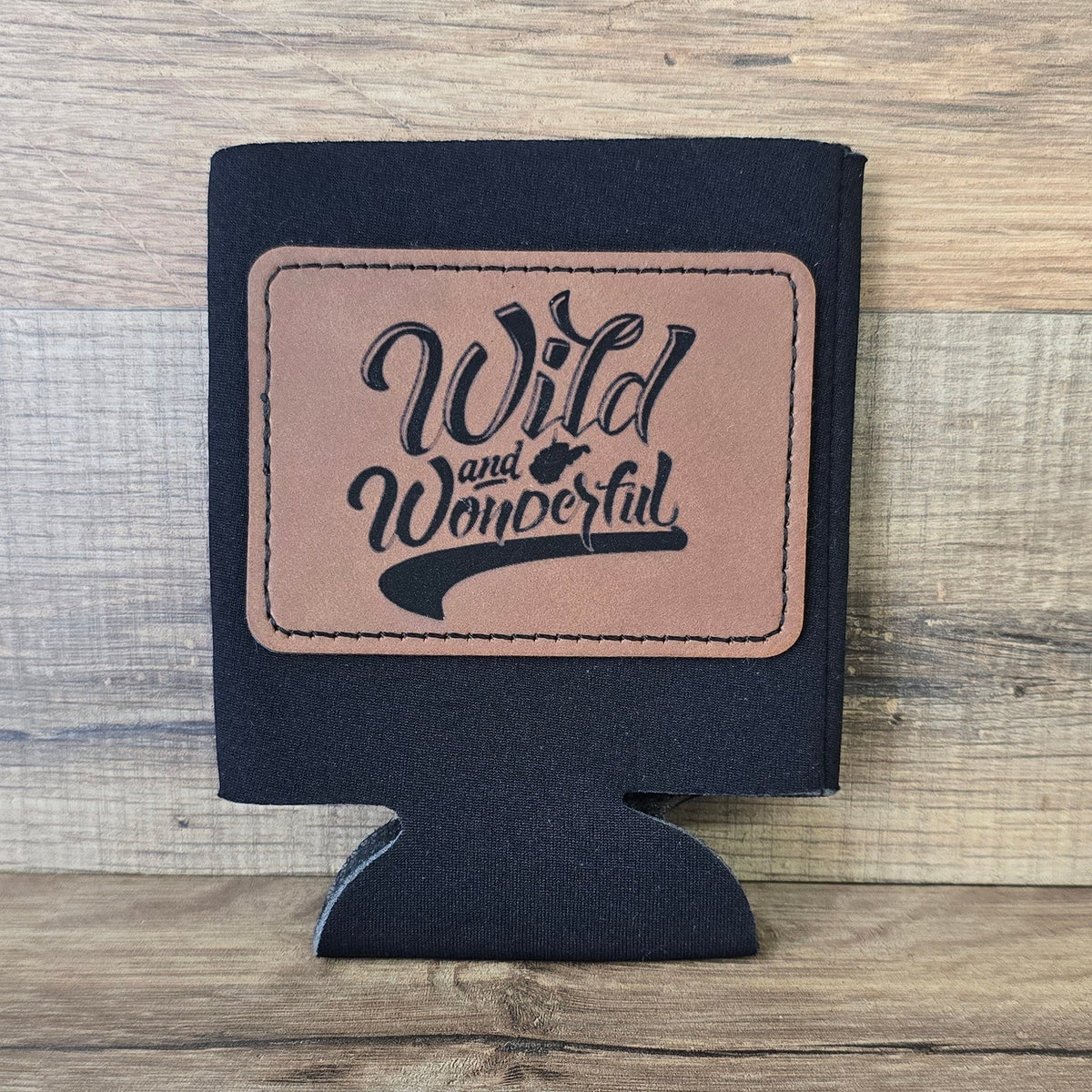 Allen's Bootery black foam can koozie with a brown leather patch featuring Wild and Wonderful text
