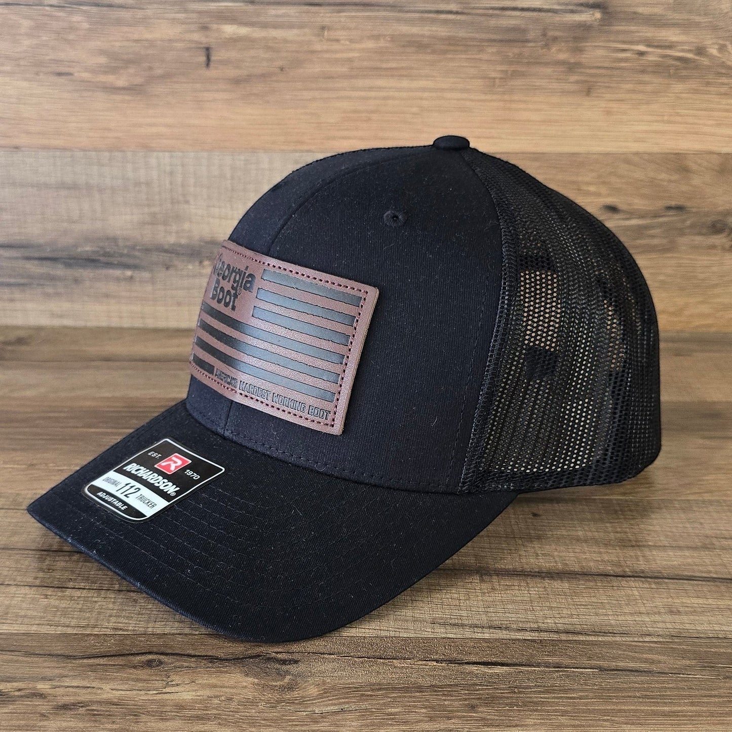 Allen's Bootery black Georgia Boot trucker hat with a leather flag patch and breathable mesh back.