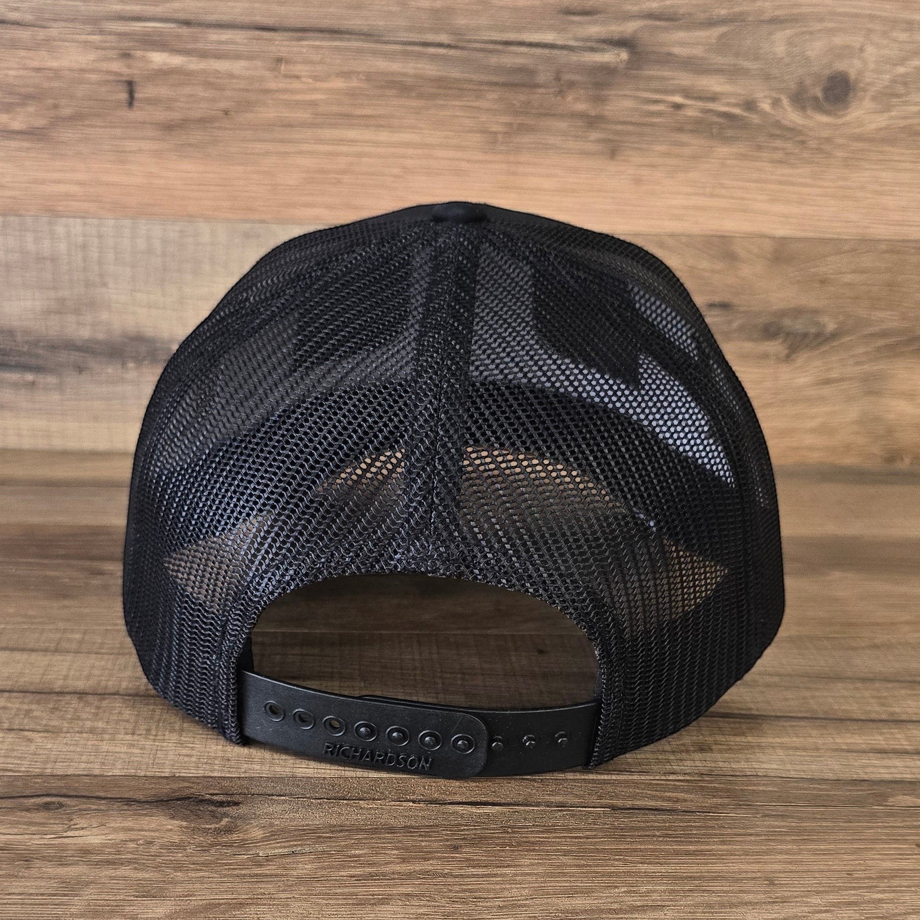 Allen's Bootery black trucker hat back view showing breathable mesh panels and adjustable plastic snapback closure.
