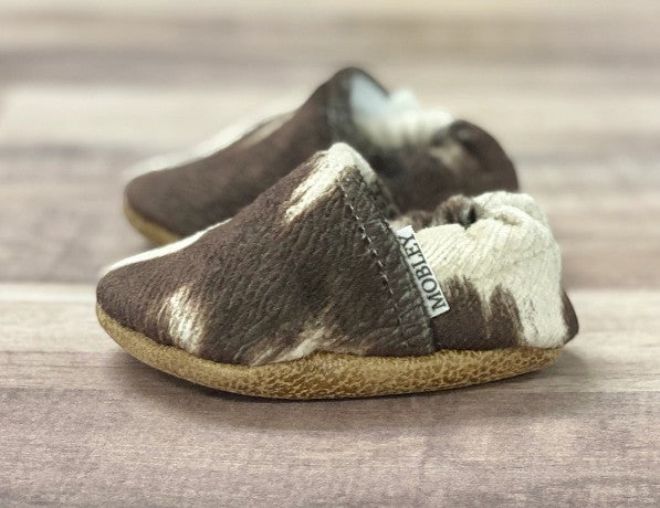 Allen's Bootery brown and white cow print soft sole infant moccasin shoes with a textured leather base.
