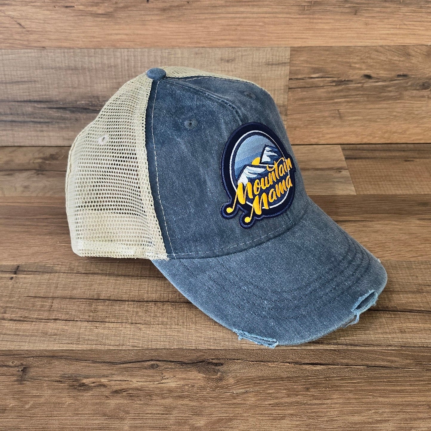 Allen's Bootery Mountain Mama trucker hat with a distressed blue brim, mesh back, and mountain landscape patch.