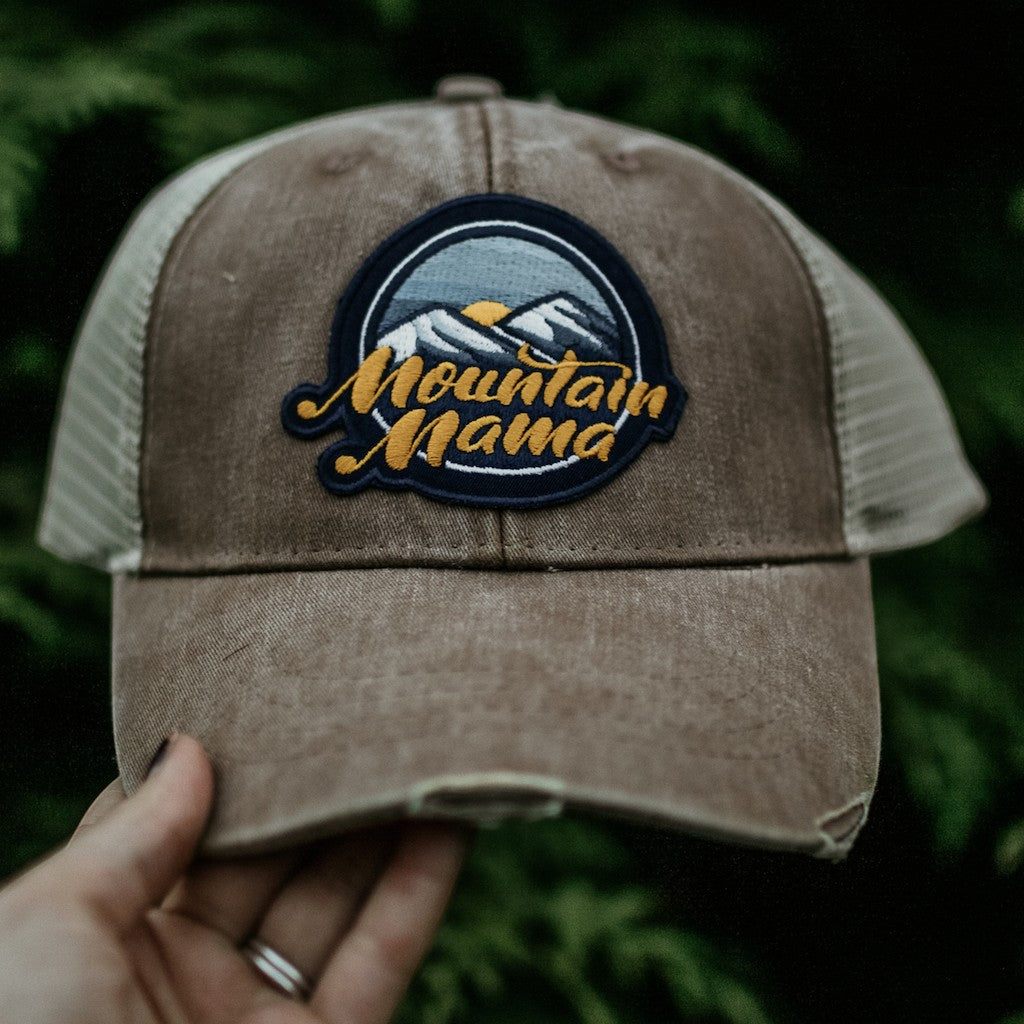 Allen's Bootery Mountain Mama trucker hat with a distressed brown brim, mesh back, and mountain landscape patch