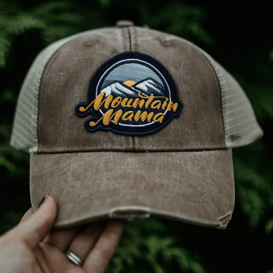 Allen's Bootery Mountain Mama trucker hat with a distressed brown brim, mesh back, and mountain landscape patch