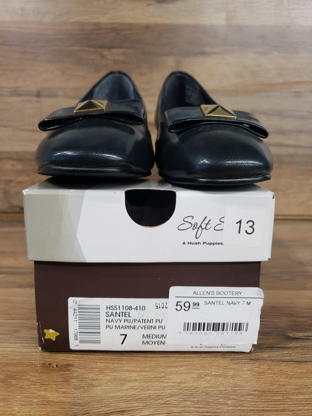 Allen's Bootery navy cap toe pumps with metal ornament and low heel displayed on their original shoe box