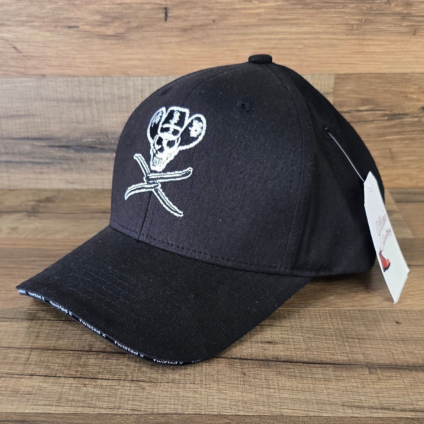 Allen's Bootery black Twisted X ball cap featuring an embroidered skull wearing a cowboy hat on a wood background