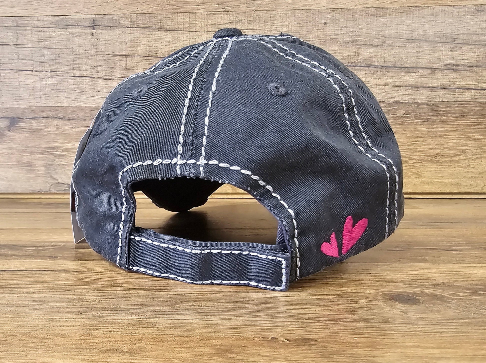 Allen's Bootery black distressed baseball cap with white contrast stitching and pink heart embroidery on the back