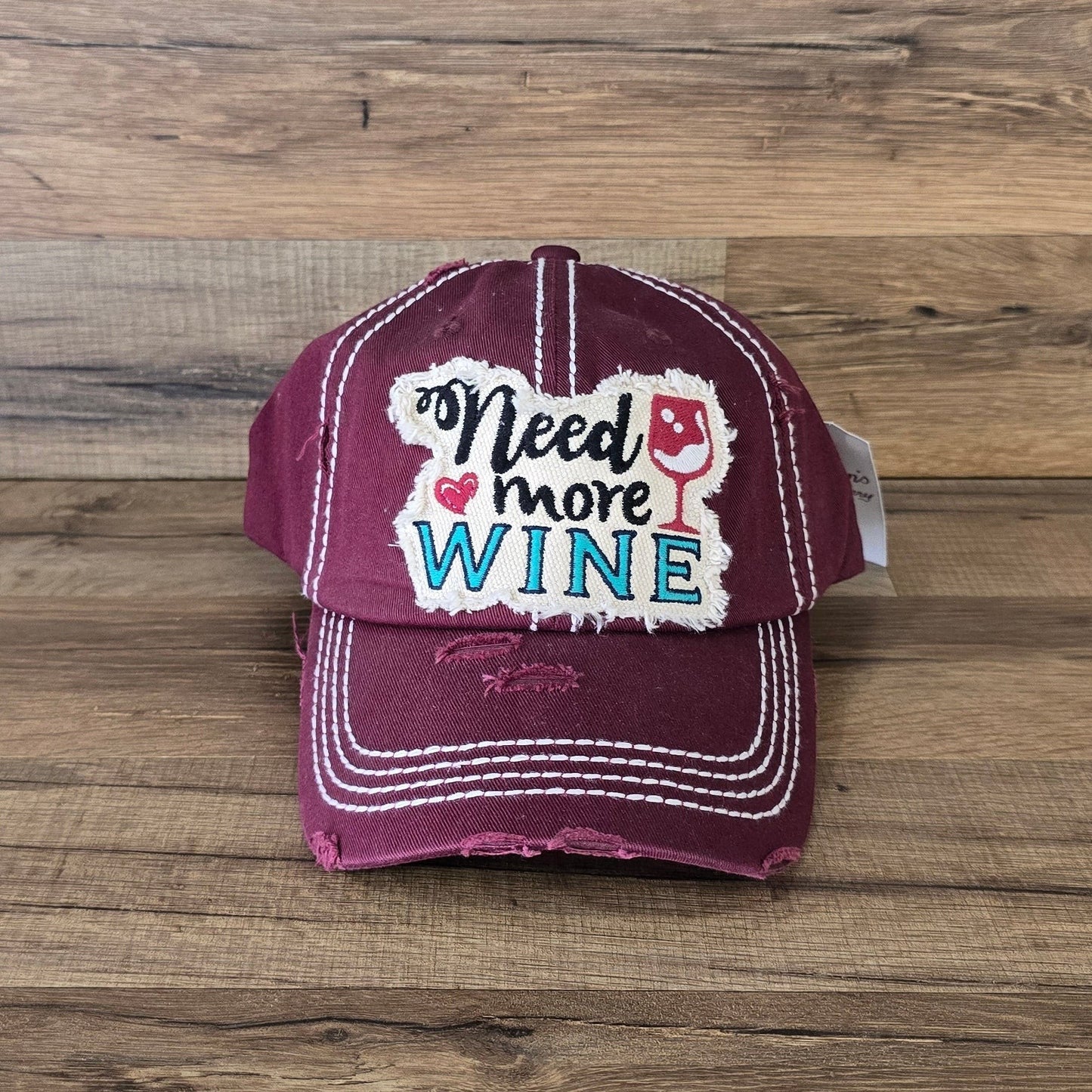 Allen's Bootery burgundy distressed cotton baseball cap with Need More Wine embroidered patch and white stitching
