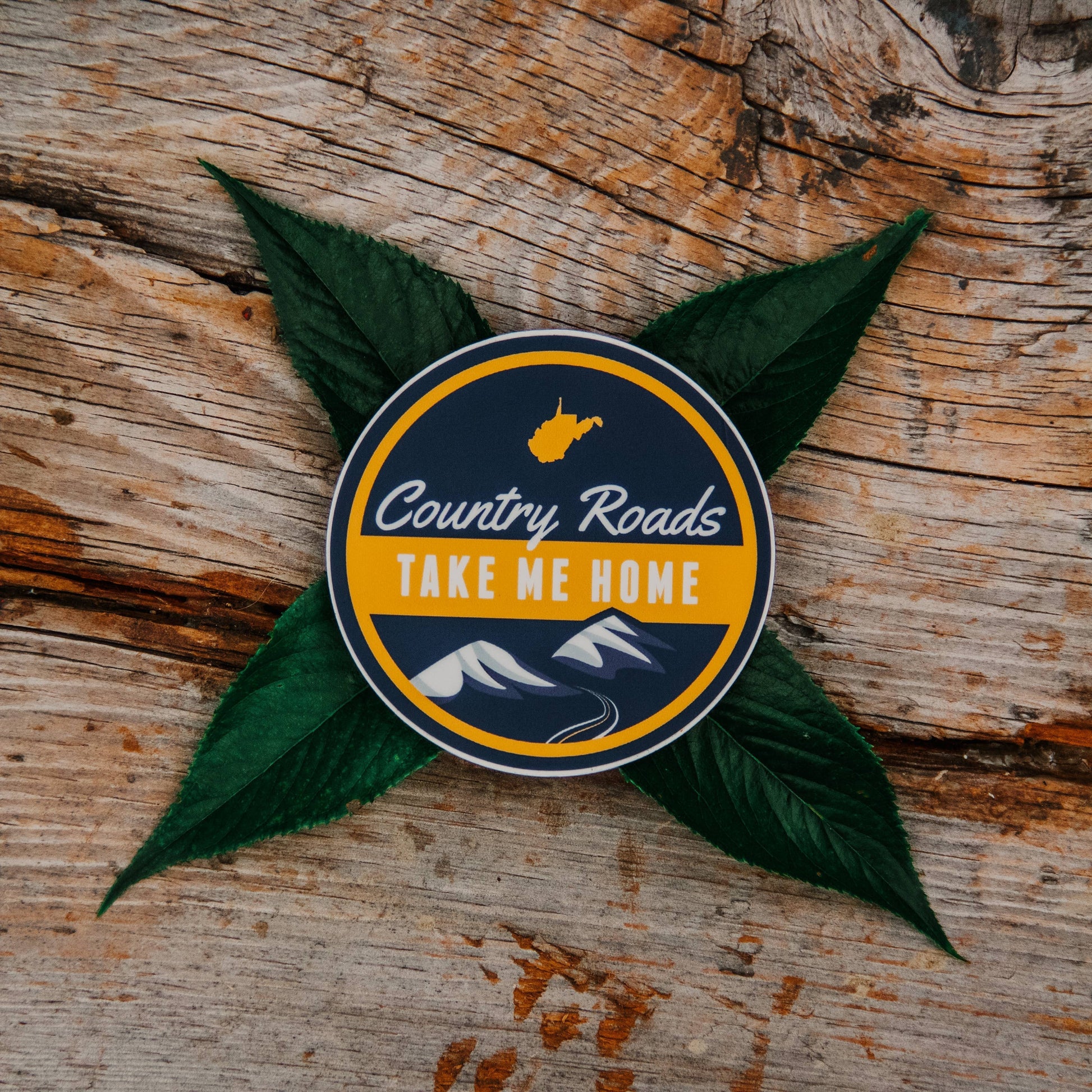 Allen's Bootery Country Roads sticker featuring West Virginia map, mountains, and text on a rustic wood background.