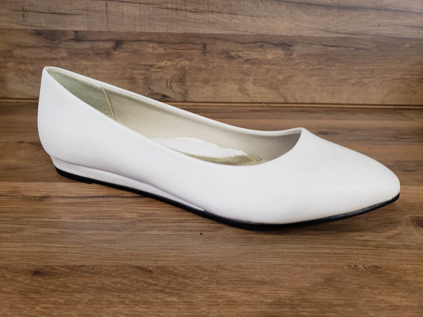 Allen's Bootery Darlene white leather flat shoe with a low heel and synthetic sole on a wood background