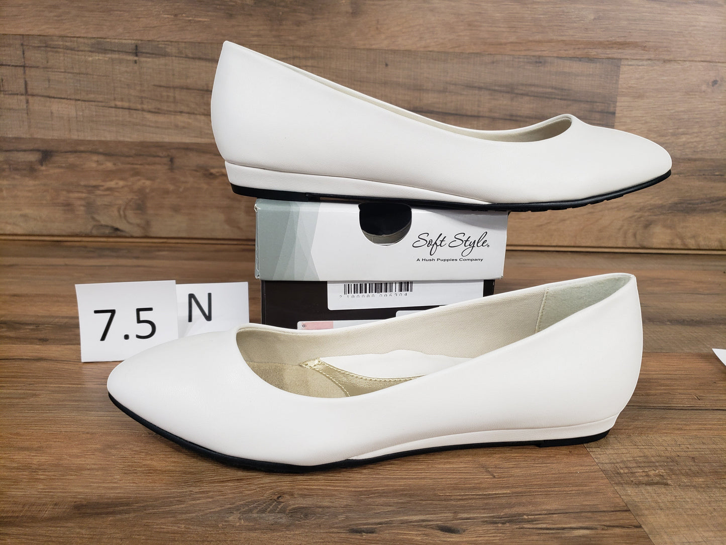 Allen's Bootery Darlene white leather flat shoes with a low heel and synthetic sole on a wooden background.