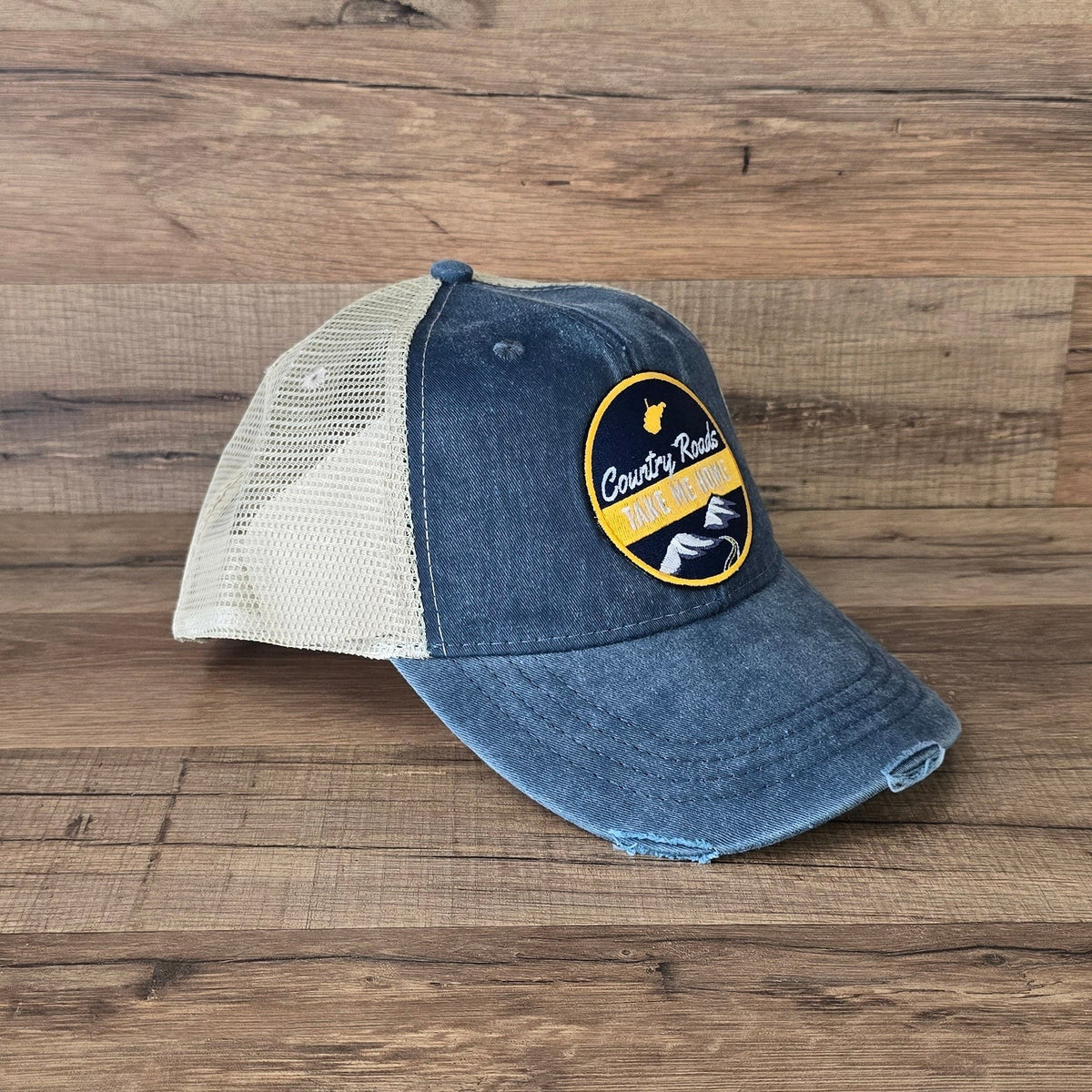 Allen's Bootery distressed blue denim trucker hat with tan mesh back and Country Roads mountain landscape patch