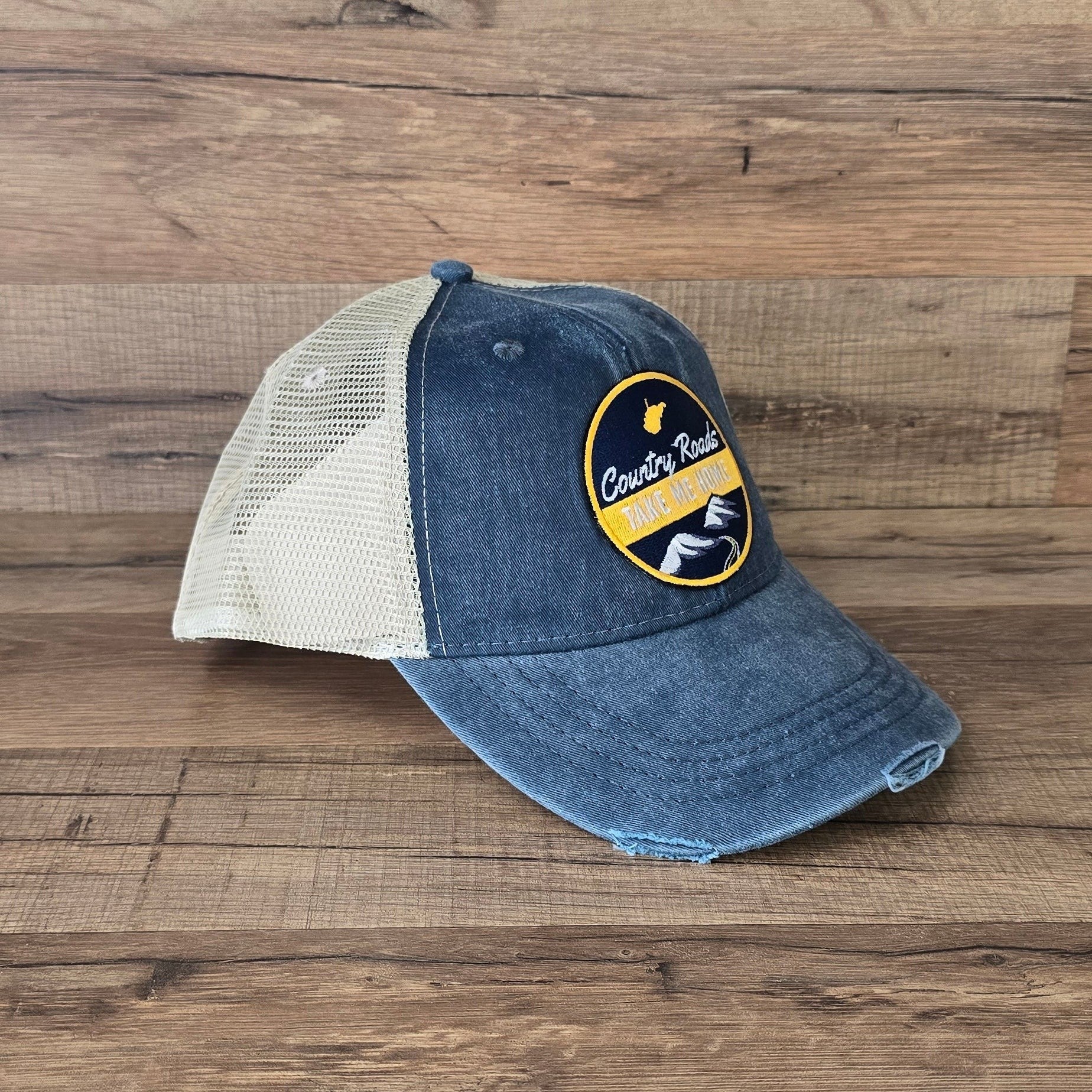 Allen's Bootery distressed blue denim trucker hat with tan mesh back and Country Roads mountain landscape patch