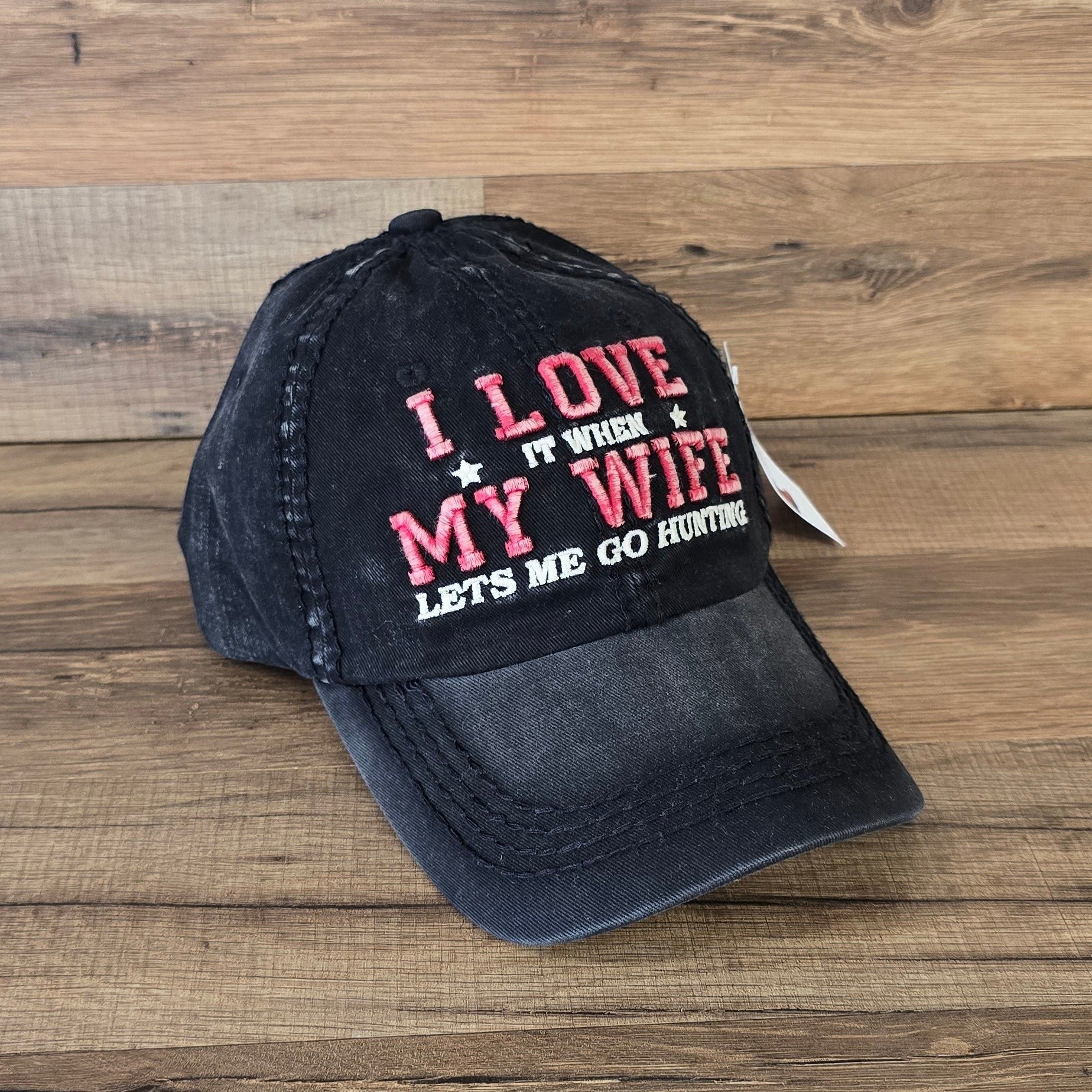 Allen's Bootery black distressed cotton baseball cap with red and white embroidered hunting slogan on wood background