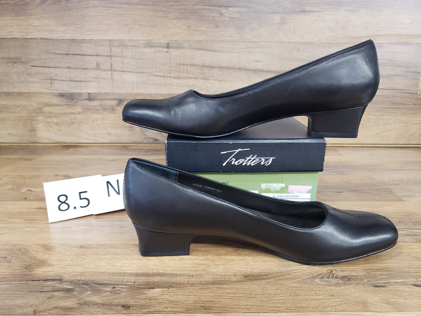 Allen's Bootery Doris black leather pumps with a low block heel and v-gore detail, displayed on a shoe box.