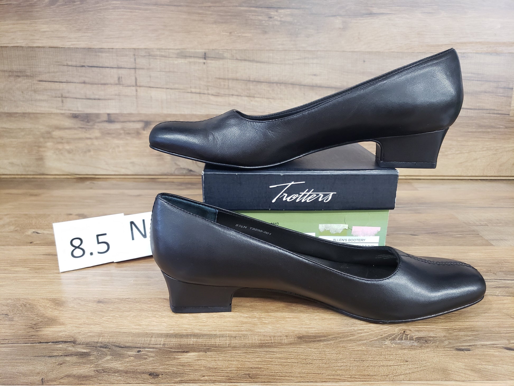 Allen's Bootery Doris black leather pumps with a low block heel and v-gore detail, displayed on a shoe box.