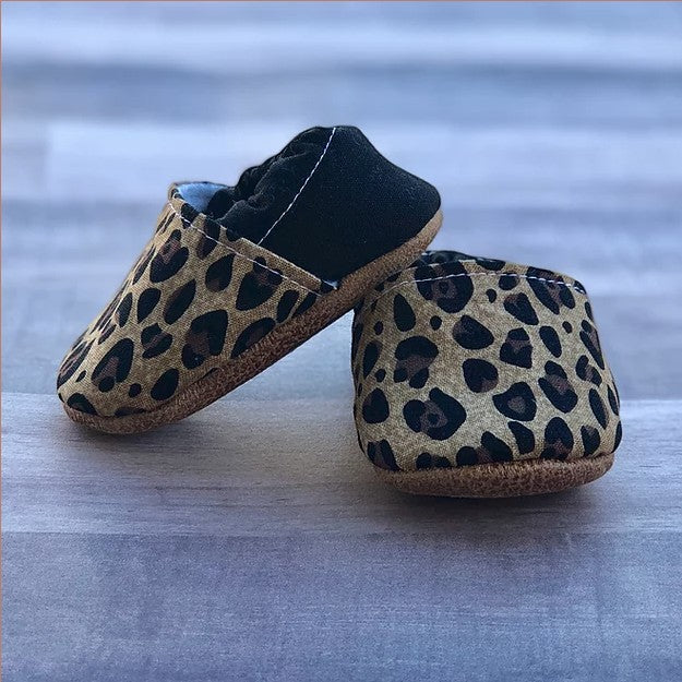 Allen's Bootery infant moccasins featuring a trendy leopard print pattern with a black heel and soft flexible soles.