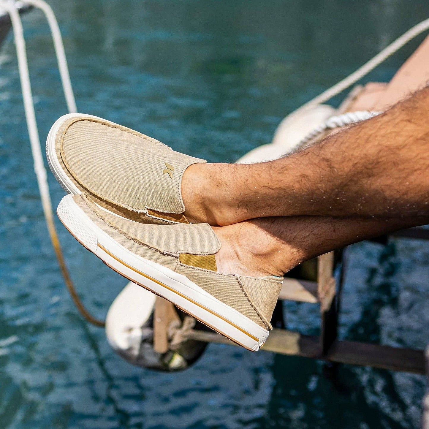Allen's Bootery Men's tan canvas slip-on boat shoes with fish print insoles and non-marking rubber soles.