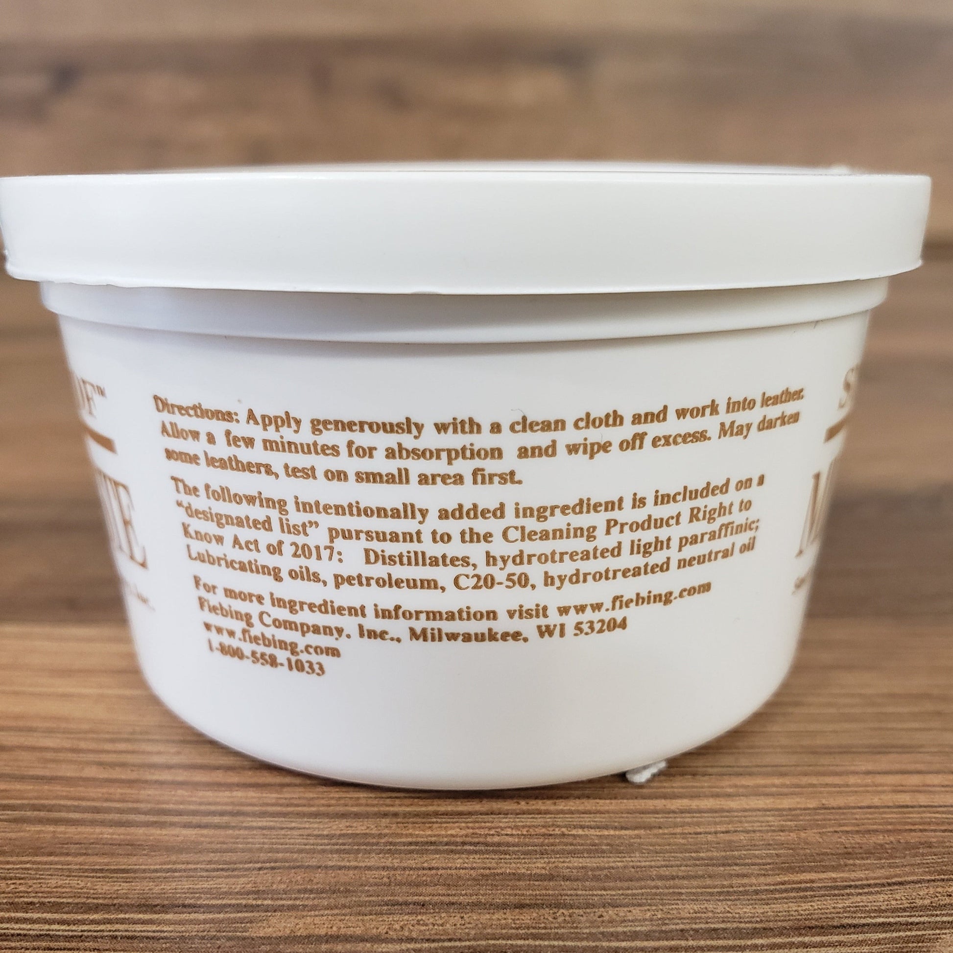 Allen's Bootery Snow-Proof Mink Oil paste container showing application instructions on a wooden surface
