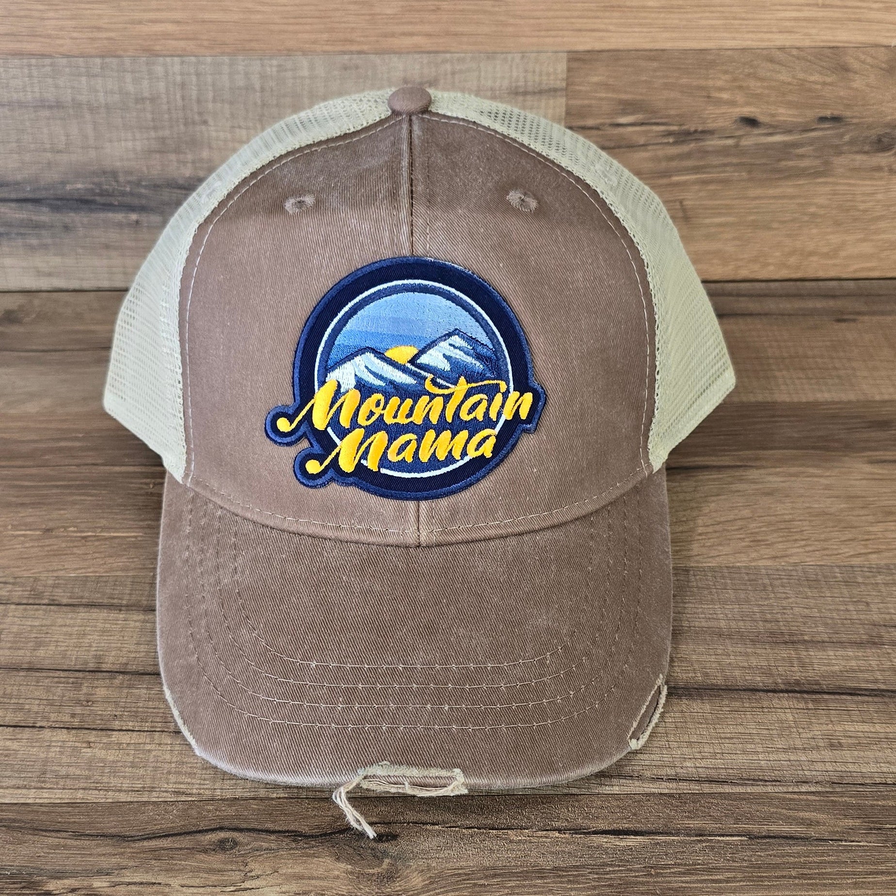 Allen's Bootery Mountain Mama trucker hat with a distressed brown brim, mesh back, and mountain landscape patch.