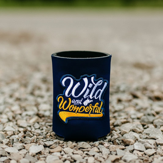 Allen's Bootery navy blue can cooler featuring a Wild and Wonderful embroidered patch on a gravel background.