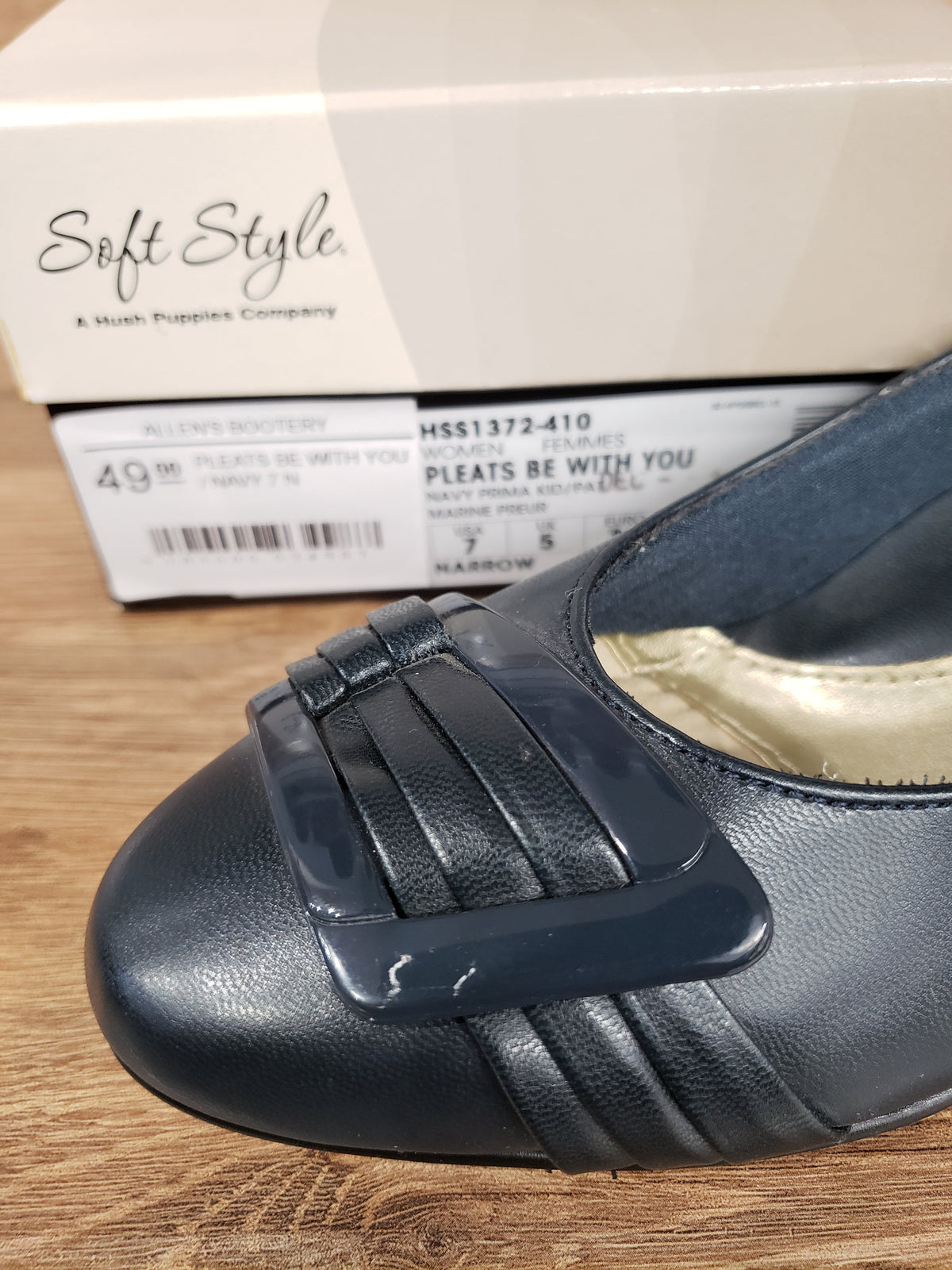 Allen's Bootery navy Pleats Be With You pump with a pleated toe detail and patent buckle, shown with its shoe box.