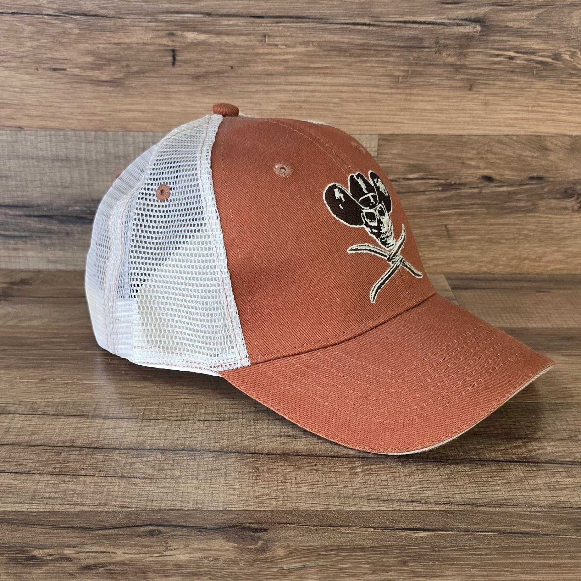 Allen's Bootery orange trucker hat with white mesh back and embroidered skull cowboy hat graphic on front panels.