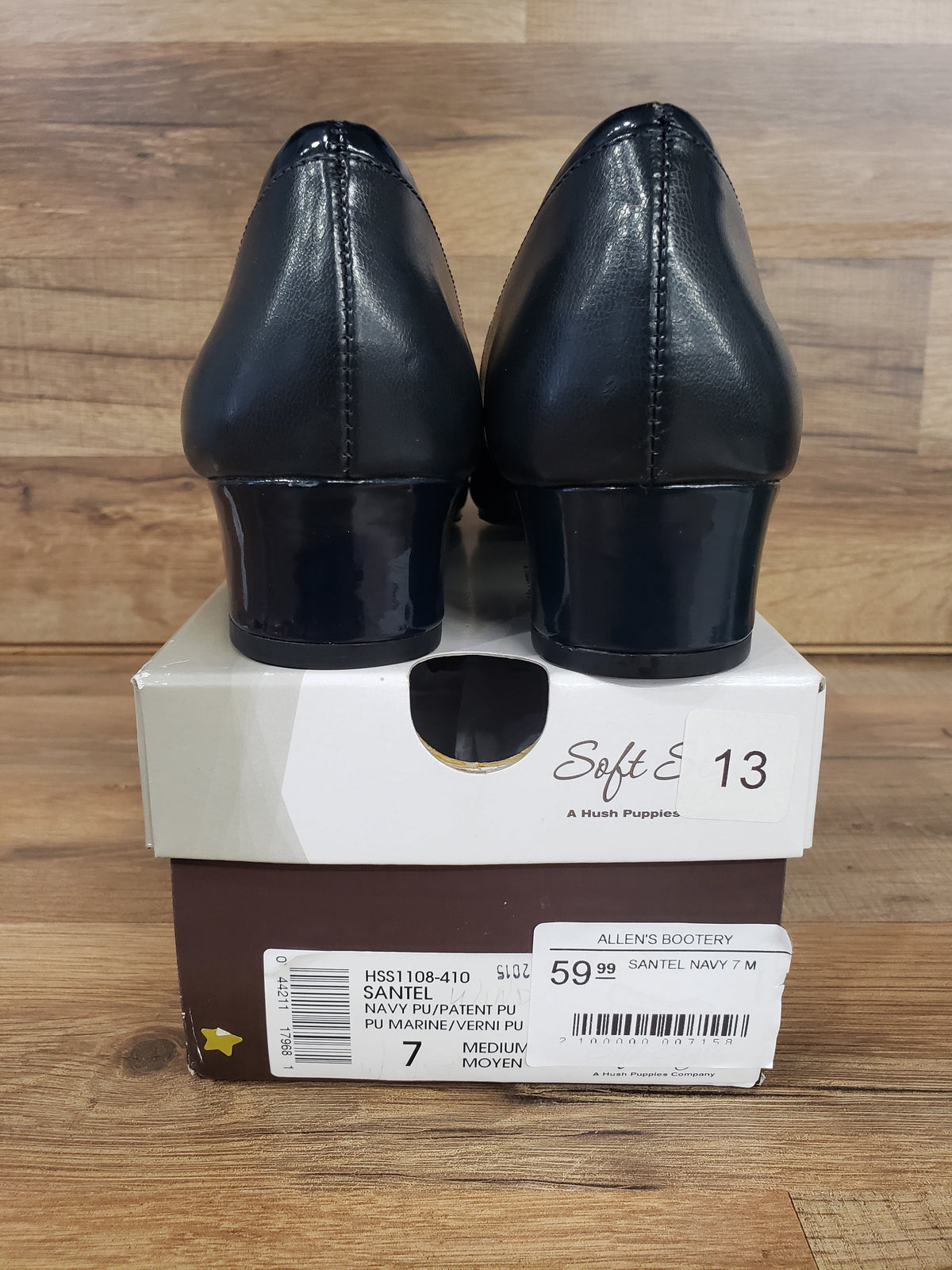 Allen's Bootery Santel navy pumps with low block heels and patent leather details, shown from the back on a shoe box.