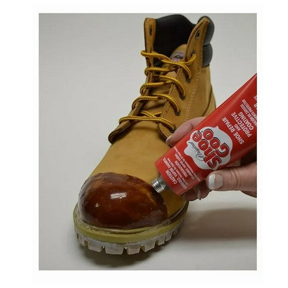 Allen's Bootery Shoe Goo Clear 3.7 oz adhesive being applied to a tan work boot toe for repair and protection.