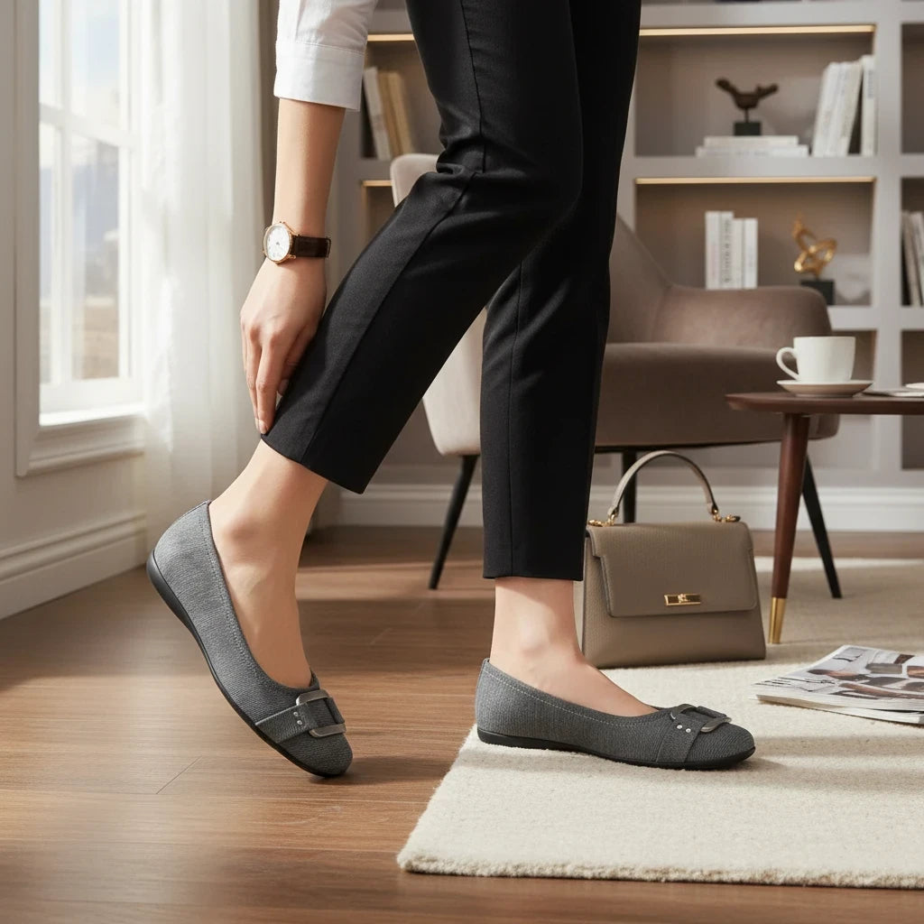 Allen's Bootery Sizzle grey metallic ballerina flats with a decorative metal buckle on the toe, worn in a home office.