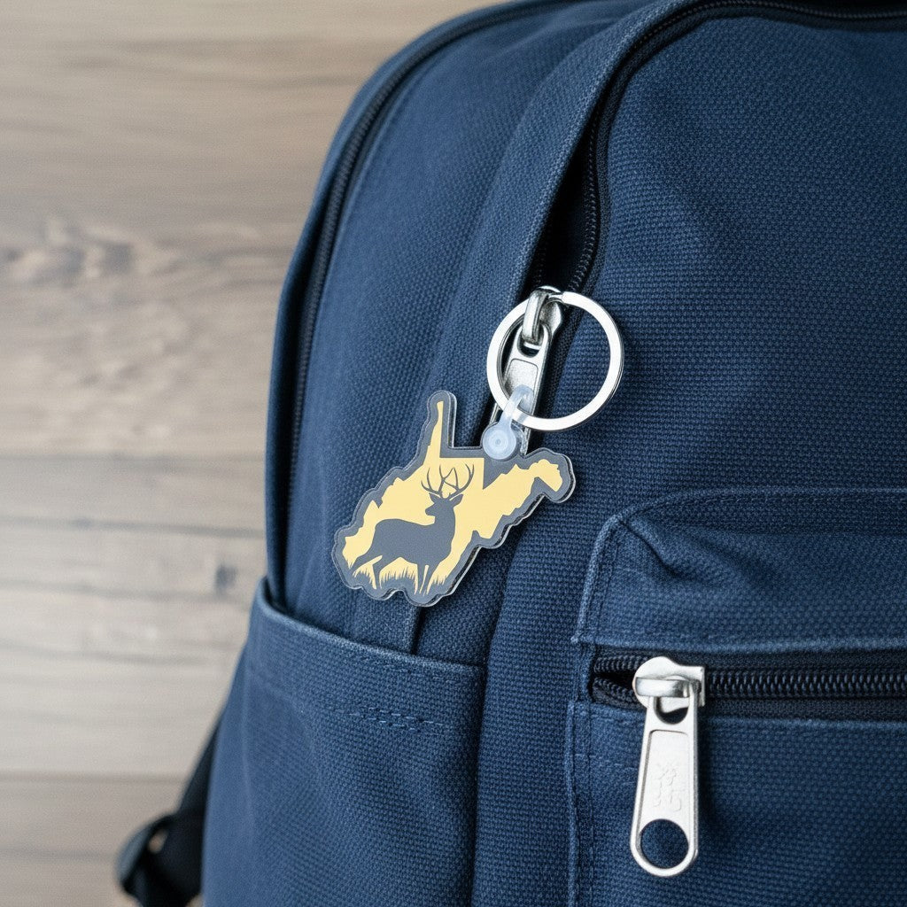 Allen's Bootery acrylic West Virginia state-shaped keychain with a deer silhouette design attached to a blue backpack