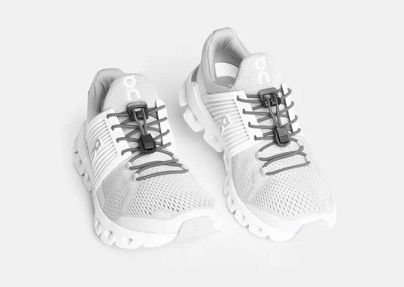 Allen's Bootery Xpand gray elastic quick release laces installed on white athletic sneakers with locking anchors