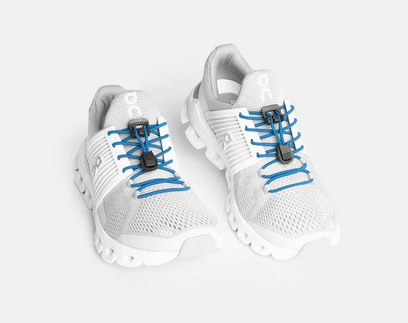 Allen's Bootery Xpand True Blue elastic laces installed on white athletic sneakers for a quick-release slip-on fit.